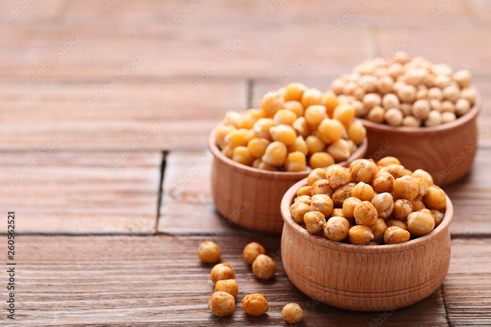 Roasted and dry chickpeas in bowls on brown wooden table Roasted and dry chickpeas in bowls on brown wooden table