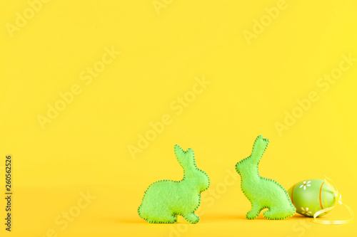 Fabric rabbits with easter egg on yellow background