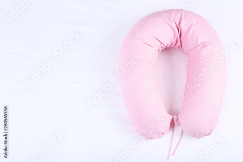 Pink body pillow on white bed