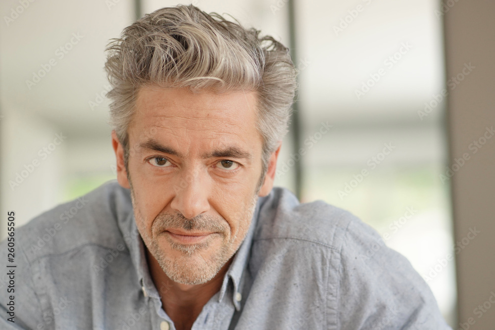 Fototapeta premium Portrait of handsome mature man looking at camera in contemporary home
