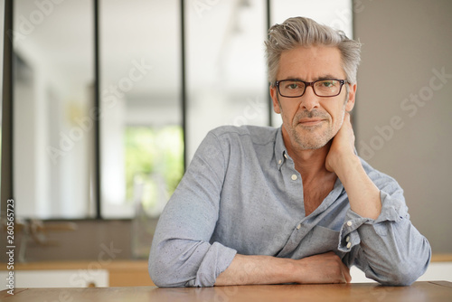 Portrait of handsome mature man wearing glasses smiling at camera © goodluz