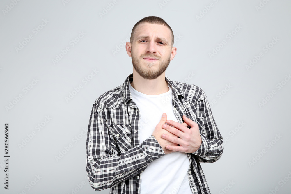 Young man having heartache on grey background Young man having heartache on grey background