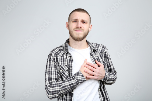 Young man having heartache on grey background