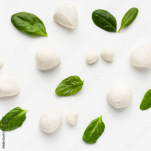 Mozarella cheese balls and basil leaves on white background