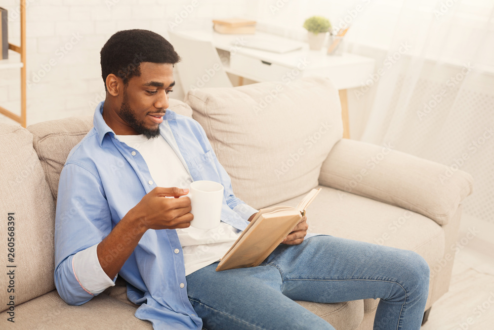 Young african-american man reading book at home