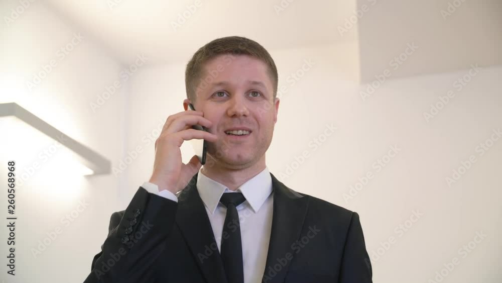 Handsome businessman in suit and tie speaking on the phone in office. Close up portrait smiling man in light white interior. Happy active handsome lawyer man calling mobile Handsome businessman in suit and tie speaking on the phone in office. Close up portrait smiling man in light white interior. Happy active handsome lawyer man calling mobile