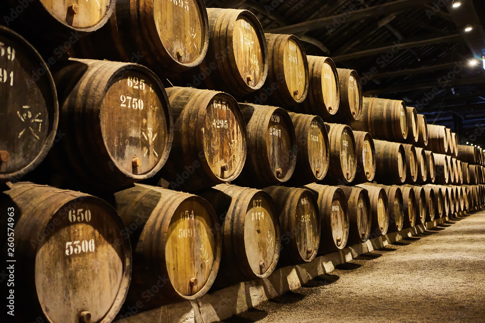 Old aged traditional wooden barrels with wine in a vault lined up in cool and dark cellar in Italy, Porto, Portugal, France Old aged traditional wooden barrels with wine in a vault lined up in cool and dark cellar in Italy, Porto, Portugal, France