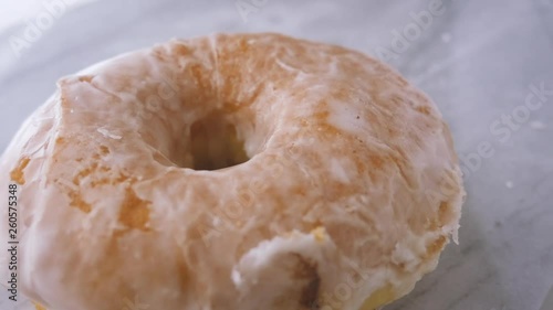 Plain glazed donut falling in slow motion. The simple iced pastry drops and bounces on a marble countertop to celebrate National Donut Day. Gourmet doughnuts are a modern, trendy food craze. photo