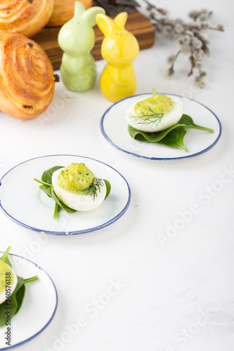 Deviled eggs with avocado and spinach and roll buns on festive Easter table