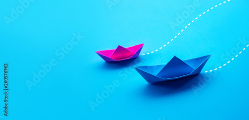 Business competition or partner concepts with two boat paper on blue worktable background photo