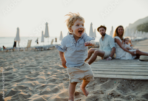 Young family with toddler children having fun on beach on summer holiday.