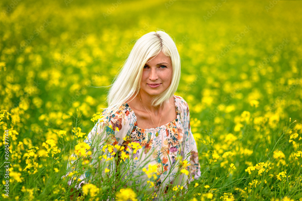 Fototapeta premium Soft, selective focus. Beautiful, attractive, blond woman in a yellow flower meadow.