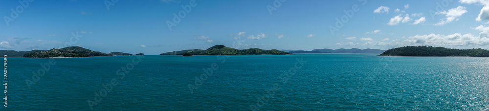 Whitsunday Island, Australia - February 16, 2019: Wide panorama shot of Whitsunday Island group with Hamilton Island to the left and Whitsunday in center. Azur sea and blue sky. Whitsunday Island, Australia - February 16, 2019: Wide panorama shot of Whitsunday Island group with Hamilton Island to the left and Whitsunday in center. Azur sea and blue sky.