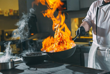 Chef is stirring vegetables in wok.