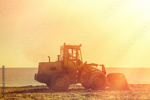 Bulldozer against the sea and sunset sky. Skyline. Tint. Copy