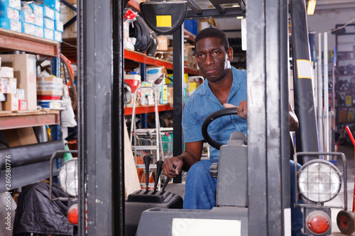 African American worker of building materials warehouse working on forklift truck © JackF