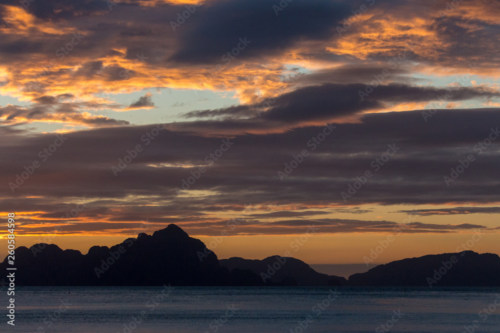 Philippines isles at sunset. Scenic sunset above sea. Travel and summer vacation concept. Island silhouette in evening dusk. Calm evening on tropical coast. Twilight at sea. 