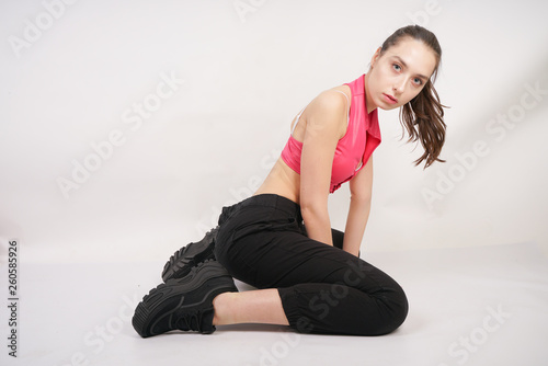 young beautiful caucasian teenager girl in a modern sports suit before training on a white background in the Studio alone