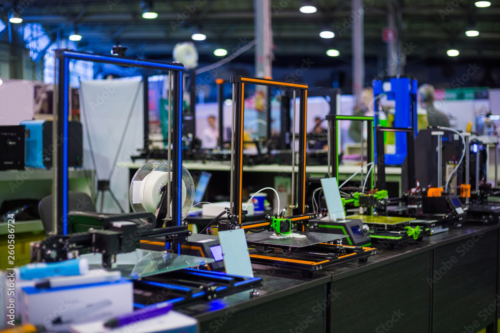 Automatic 3D printers in row during work at modern technology exhibition. 3D printing, additive technologies, 4.0 industrial revolution and futuristic concept