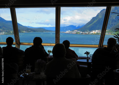 Silhouettes of people on a cruise ship looking out a window while coming into a port in Alaska.