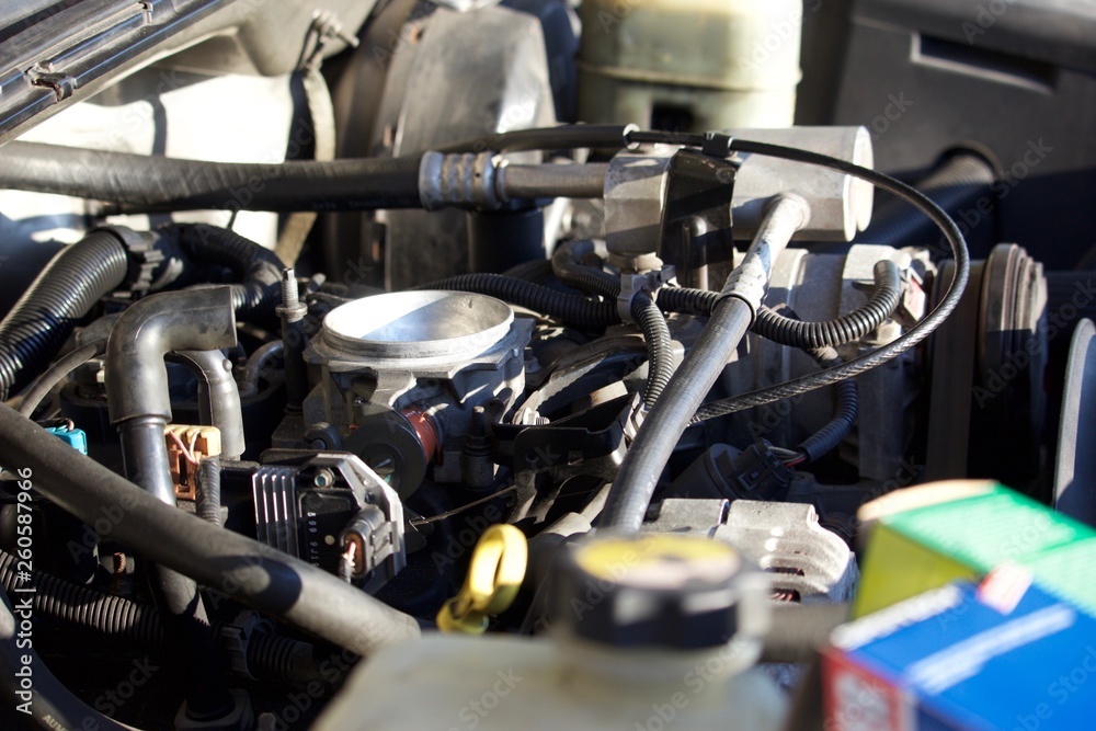Obraz premium Engine compartment without air cleaner assembly, showing throttle body and components, with parts boxes in foreground, out of focus