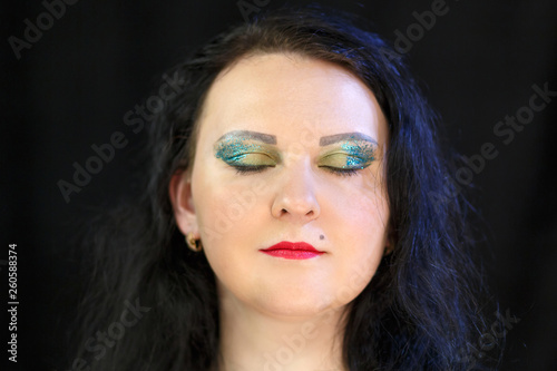 Fototapeta Naklejka Na Ścianę i Meble -  The face of a young brunette with bright makeup and closed eyes.