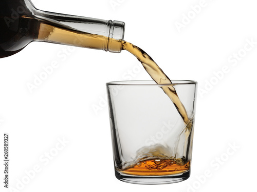 Whisky from a bottle flows in a glass. Isolated on a white background