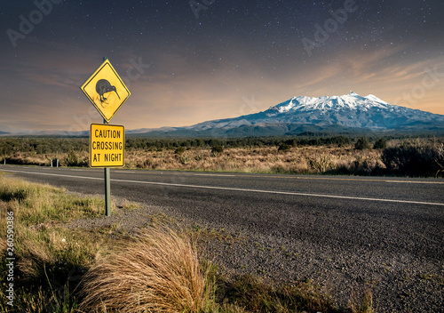Konstfotografi Kiwi crossing sign at night next to snowy Mount Ruapehu in New Zealand's Tongariro national park