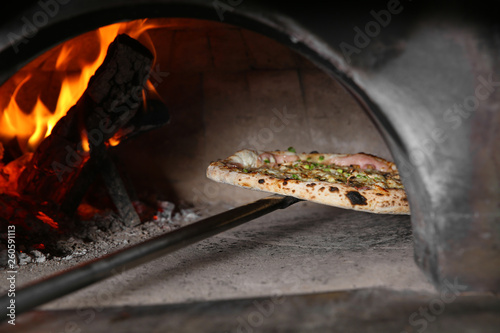 Taking out tasty pizza from oven in restaurant kitchen