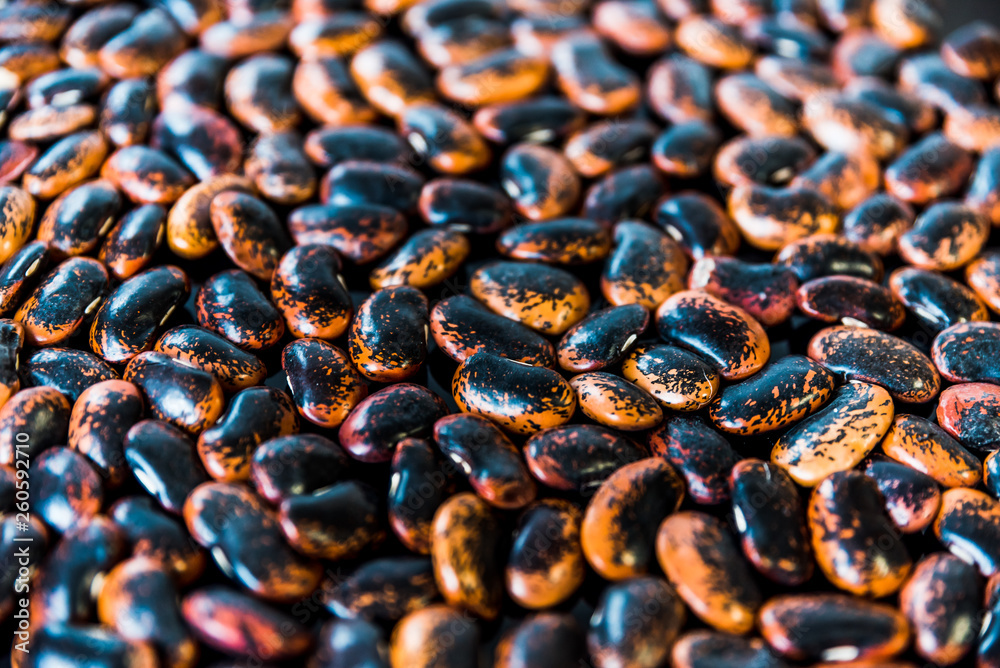 a heap of black-brown beans on black background