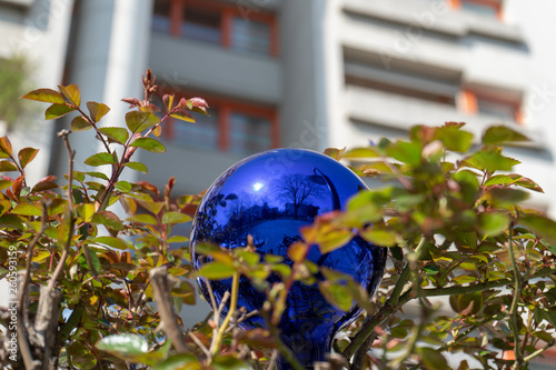 Blaue Blumenkugel vor einem Wohnhaus (Gemeindebau) in Blätterkleid photo