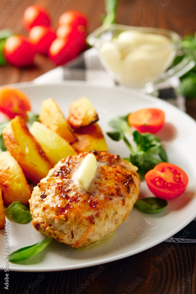 Fried chicken cutlet with potato slices served with tomato cherry and corn salad. Traditional belorussian food - roasted minced meat and potato Fried chicken cutlet with potato slices served with tomato cherry and corn salad. Traditional belorussian food - roasted minced meat and potato