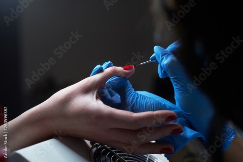Closeup hands. Manicure procedure in progress - Beautician master applying color nail polish.
