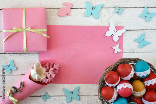 Wielkanocne tło z kolorowymi pisankami, różowym papierem, motylkami i zajączkami
