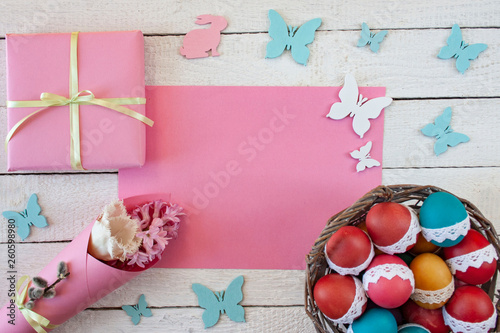 Wielkanocne tło z kolorowymi pisankami, różowym papierem, motylkami i zajączkami