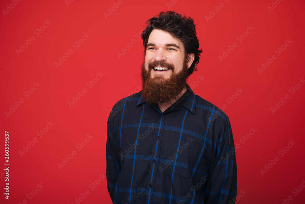 Fototapeta premium A smiling man over red background looking far away