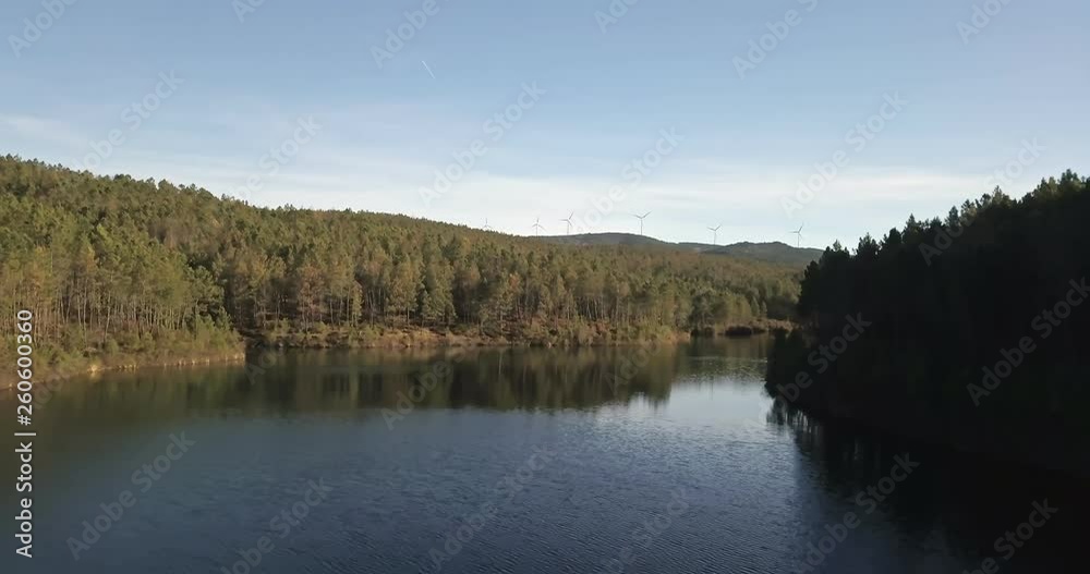View of Varzea dam on the Paiva river, artificial lake, with forest and windmills as background, in Portugal View of Varzea dam on the Paiva river, artificial lake, with forest and windmills as background, in Portugal