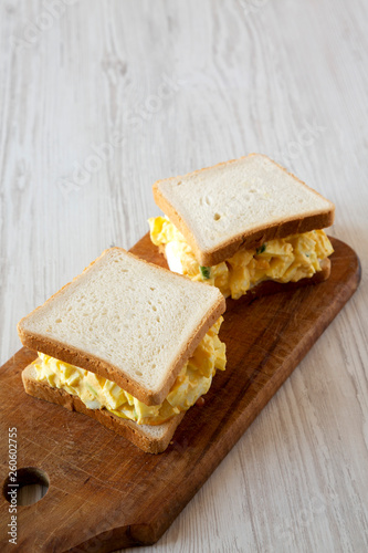 Homemade egg salad sandwich on wooden board, low angle view. Copy space.