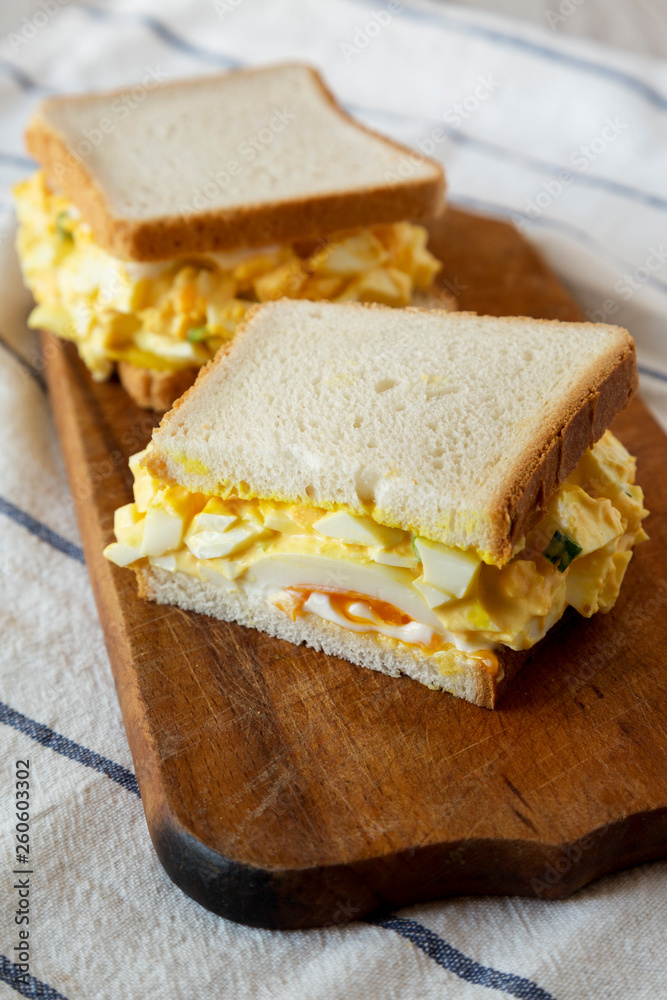 Homemade egg salad sandwich on wooden board, low angle view. Closeup. Homemade egg salad sandwich on wooden board, low angle view. Closeup.