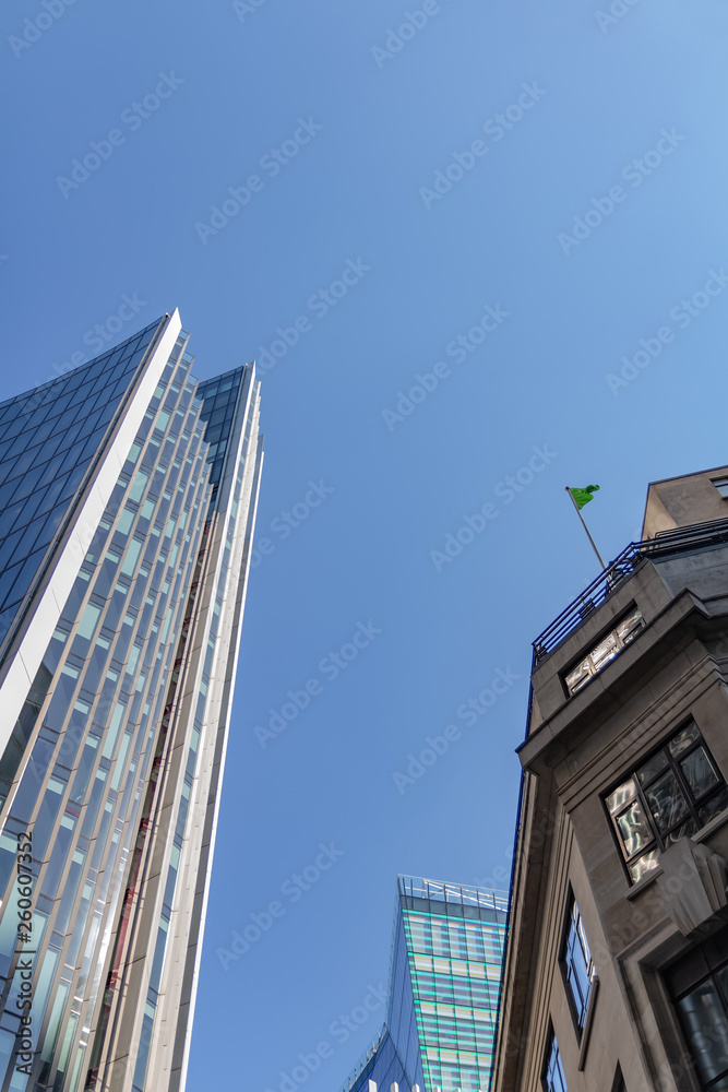 Old and new building  facades together at a bright sunny day on the blue sky background. Economy finances and business activity concept. Low angle view