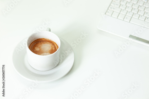 Coffee cup, laptop and on white table. Selective focus.