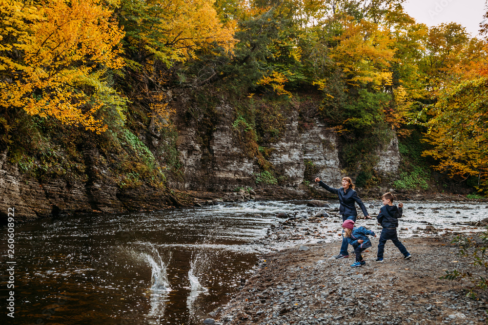 grandmother and grandchildren throwing rocks at the river at fall grandmother and grandchildren throwing rocks at the river at fall