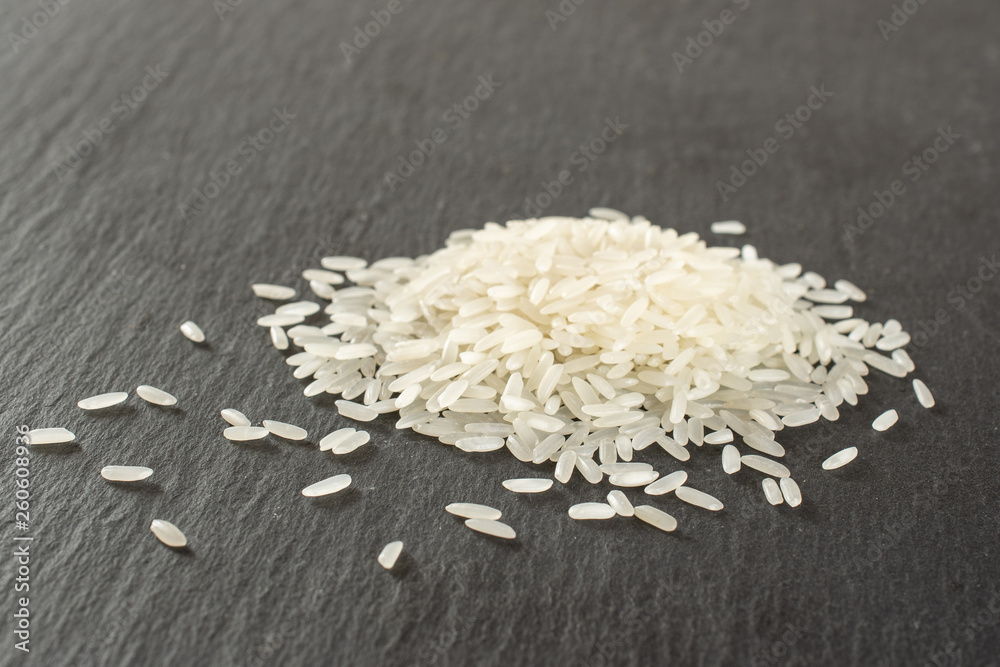 Lot of whole white jasmine rice grains on grey stone Lot of whole white jasmine rice grains on grey stone