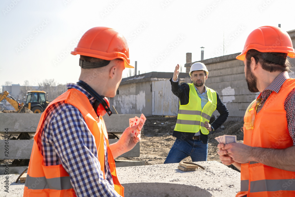 chief man shouts at the workers in the helmet who are resting and do not want to work