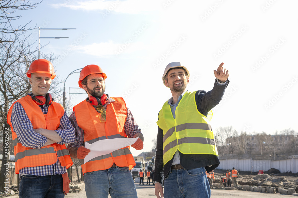 male builders workers engineers at a construction site looking drawings in helmets male builders workers engineers at a construction site looking drawings in helmets