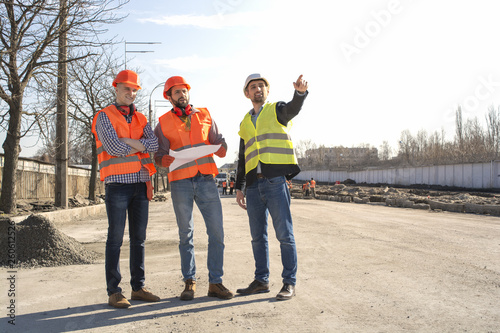 male builders workers engineers at a construction site looking drawings in helmets © Vasiliy