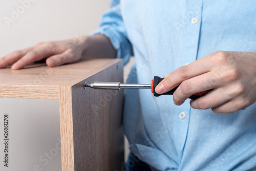 close-up of furniture Assembly with screwdriver in the hands of woman
