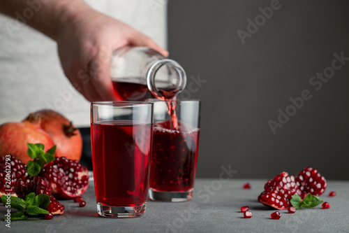 Male hand pouring pomegranate juice into a glass.