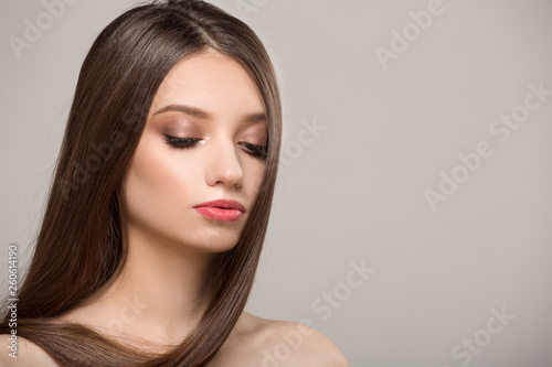 Woman with straight shiny hair. Gray background