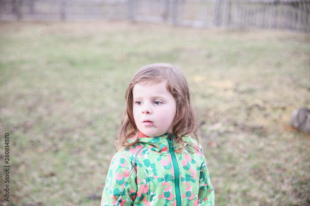 An emotional portrait of a happy little girl on the background of a cloudy mountain summit and meadow. Her emotions change. Good childhood. An emotional portrait of a happy little girl on the background of a cloudy mountain summit and meadow. Her emotions change. Good childhood.